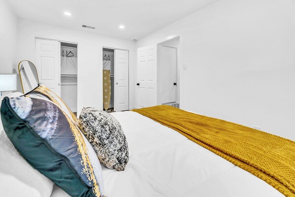 A bedroom with a bed, white walls, two doors, and a yellow blanket. - New! Walk to FIFA 2026 Football Games Dallas /AT&T Stadium! TX LIVE! Globe Life (Arlington)