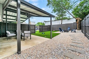 A covered patio area with outdoor furniture, a small lawn, and a wooden fence. - New! Walk to FIFA 2026 Football Games Dallas /AT&T Stadium! TX LIVE! Globe Life (Arlington)