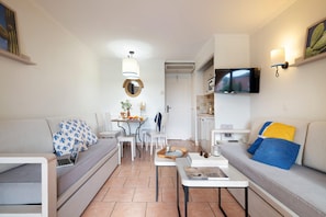 A modern living room with a sofa, a coffee table, a dining area with chairs, and a TV mounted on the wall. - Luxury 4-person Riviera Sanctuary (Roquebrune-sur-Argens)