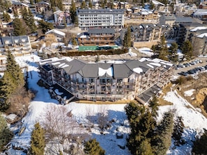 Un hotel de varios pisos con balcones, estacionamiento y alrededores cubiertos de nieve.