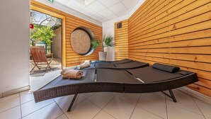 A room with wooden panel walls, a massage table, a chair, and a potted plant. - 2-bedroom Beach Cottage (Fort-Mahon-Plage)