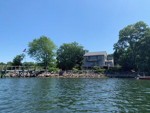 A waterfront property with a dock, a flag, and a multi-story building. - Spacious, sunlit, seaside 4-bedroom, 3 bath waterfront house w/ AC in Warren, RI (Warren)