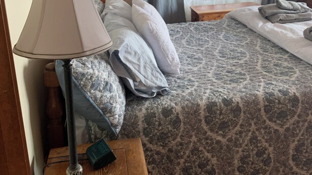 A bedroom with a bed, a lamp, a dresser, and a window with curtains. - Spacious, sunlit, seaside 4-bedroom, 3 bath waterfront house w/ AC in Warren, RI (Warren)