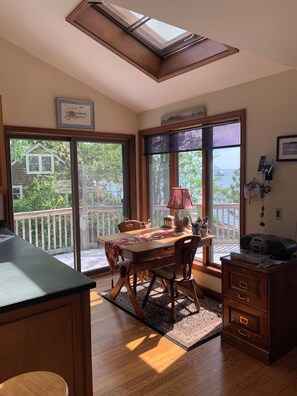 Uma área de refeições com mesa, cadeiras, uma luminária e vista para o exterior.