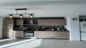 Een moderne keuken met een zwart en houten kleurenschema, een ingebouwde magnetron en een hanglamp.