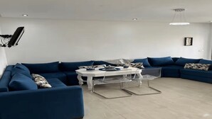 Een moderne woonkamer met een modulaire bank, een klein rond tafeltje en een transparante glazen salontafel.