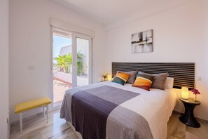 A bedroom with a bed, a bench, a nightstand, and a view through a sliding door. - Mediterranean & golf dreams (Mutxamel)