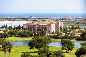 A hotel with a large building, a golf course, and a body of water. - Mediterranean & golf dreams (Mutxamel)