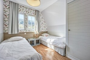 A bedroom with two beds, a window, a lamp, and a door. - Houlgate Duplex for 8 With Spa (Houlgate)
