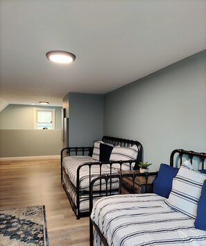 Camera da letto con due letti, pavimento in legno, una finestra e una lampada a soffitto.