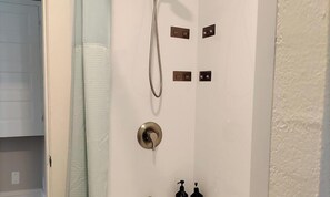 Un bagno con doccia, un porta asciugamani e una porta con serratura.