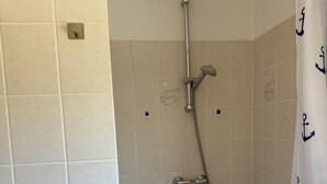 A bathroom with a shower, a bathtub, and a curtain with anchor patterns.