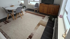 A modern living room with a dining area, a TV, and a radiator. - Cozy bright 1 room apartment in Bramsche max. 3 persons (Bramsche)