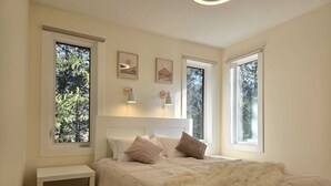 A bedroom with a bed, bedside table, and two windows. - Home away from Home in the Heart of Nature (East Kootenay G)