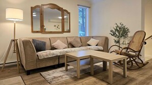 A living room with a sofa, a coffee table, a floor lamp, a rocking chair, and a mirror. - Home away from Home in the Heart of Nature (East Kootenay G)