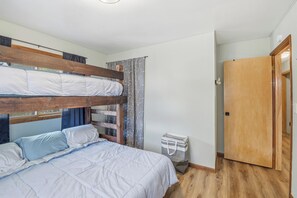 A bunk bed room with a wooden headboard, a single bed with a white duvet, a small white trash bin, and a wooden door. - Waterfront Vacation with optional pontoon rental.  Relax in the great up north! (Pound)