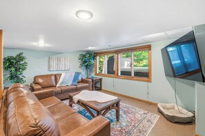 A living room with a brown leather sofa, a coffee table, and a TV mounted on the wall. - Waterfront Vacation with optional pontoon rental.  Relax in the great up north! (Pound)