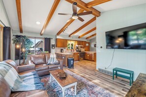A spacious living room with a leather sofa, a coffee table, and a television mounted on the wall. - Waterfront Vacation with optional pontoon rental.  Relax in the great up north! (Pound)