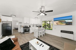 Eine moderne Küche mit weißen Schränken, einem schwarzen Kühlschrank und einem Essbereich mit weißem Tisch und Stühlen.