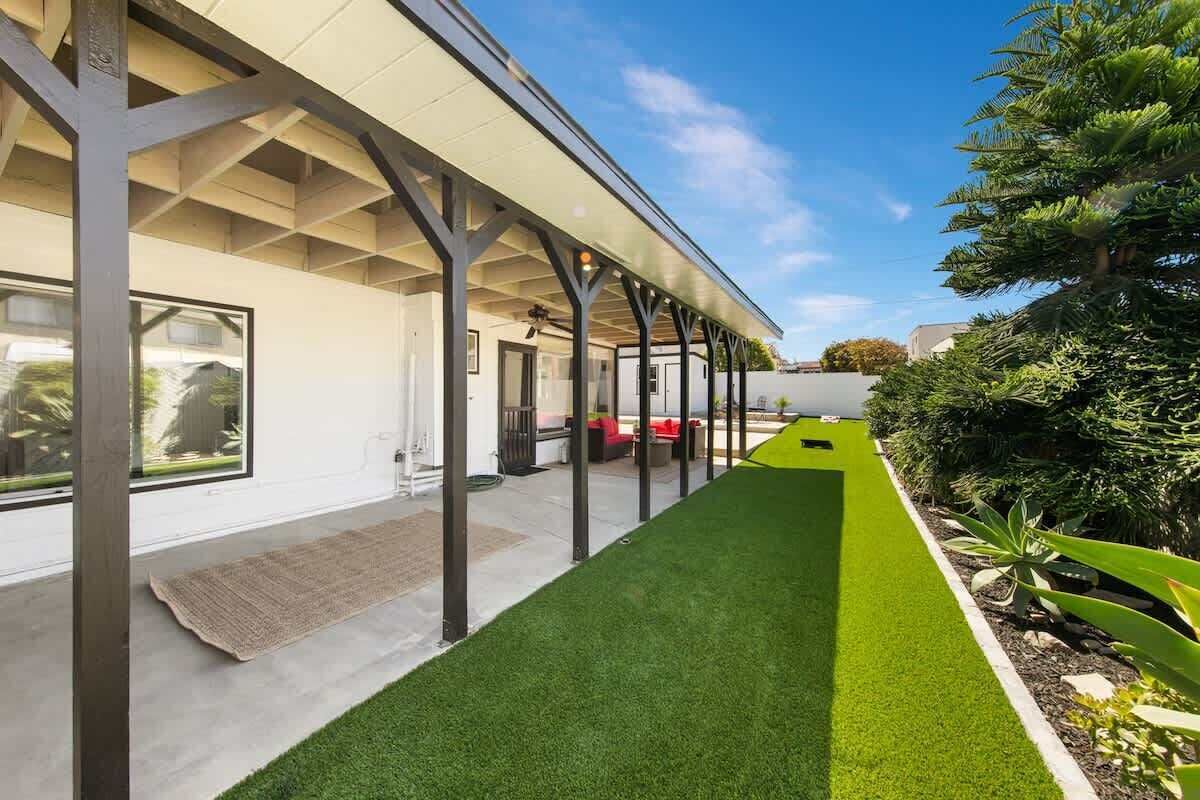 A covered outdoor area with artificial grass, a pathway, and a row of chairs.