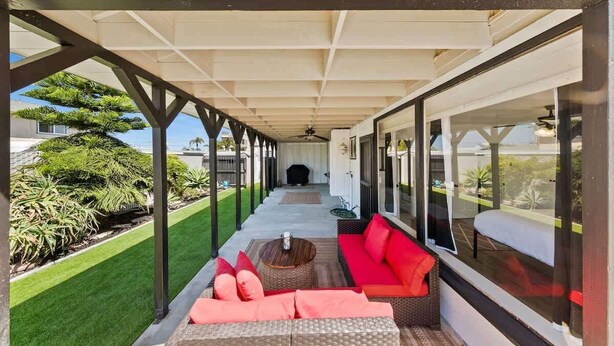 A covered outdoor seating area with a sofa, a round table, and a view of the garden and house. - 1 Bedroom Steps from Beach and Carlsbad Village (Carlsbad)