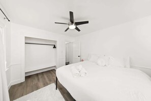 Ein heller Raum mit einem Bett, einem Deckenventilator und einem begehbaren Kleiderschrank.