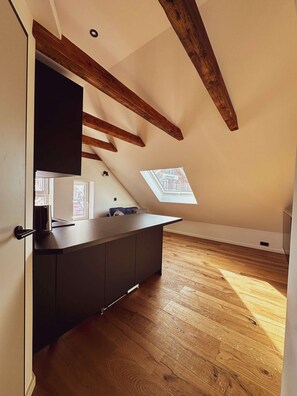 A modern kitchen with a wooden ceiling, a built-in stove, and a window overlooking the roof. - Stylish ANTJE Apartment in STRAND HAUS 10 (Borkum)