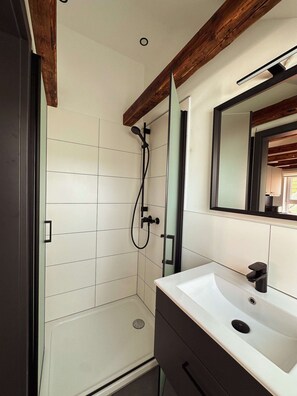 A bathroom with a shower, a sink, and a mirror. - Stylish ANTJE Apartment in STRAND HAUS 10 (Borkum)