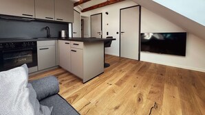 Ett modernt kök med träbjälkar, en matplats med en soffa och en tv som är monterad på väggen.