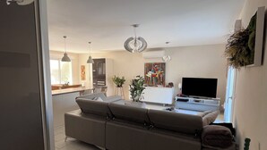 Ein modernes Wohnzimmer mit einer Couch, Fernseher und Essbereich.