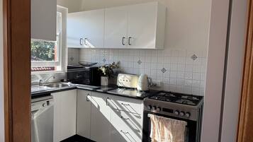 A kitchen with white cabinets, a Bosch dishwasher, a Siemens toaster, and a Beko oven.