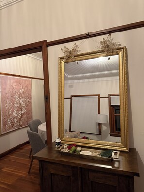 Ein Zimmer mit einem großen Spiegel, einem Tisch mit einer Blumenplatte und einem Stuhl.