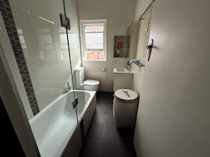 Ein kleines Badezimmer mit Badewanne, Toilette und Waschbecken.