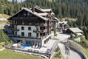 Ein mehrstöckiges Chalet mit Balkonen, einem Schwimmbad und einer Seilbahn.