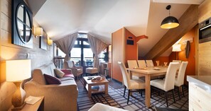Ein modernes Hotelzimmer mit Essbereich, einer Sitzecke, einem Couchtisch und Blick auf die Stadt.