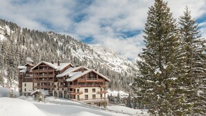 A multi-story lodge with balconies, surrounded by snow-covered mountains and trees. - Mountain Side Stay With Sauna (Araches-la-Frasse)