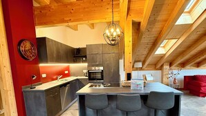 Une cuisine moderne dotée d’un îlot central, de tabourets de bar et d’un luminaire suspendu.