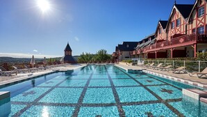 A swimming pool with a tiled pattern, lounge chairs, and a building with a balcony. - Premium Normandy Apartment for 4 (Houlgate)