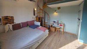 Una camera da letto con un letto, una scrivania, una scala a chiocciola e un soppalco.