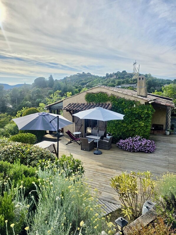 Eine Terrasse mit Gartenmöbeln, einer Pergola und Blick auf eine Hügellandschaft.