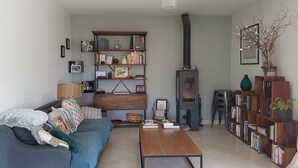 Un soggiorno con divano, tavolino, libreria e stufa a legna.