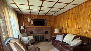 Ein Wohnzimmer mit Kamin, Fernseher und braunem Ledersofa.