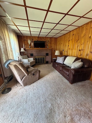 Ein Wohnzimmer mit Kamin, Fernseher und braunem Ledersofa.
