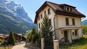Una casa a due piani con tetto spiovente, un portico e una strada privata che conduce a un ingresso con cancello.