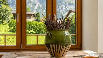 A table with a candle, a glass, and a plate set against a window with a view of mountains.
