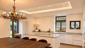 Una cucina moderna con un'isola centrale, un'area pranzo con tavolo e sedie in legno e un lampadario.