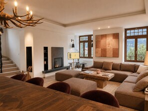 Una sala de estar moderna con chimenea, muebles de madera y ventanas amplias.