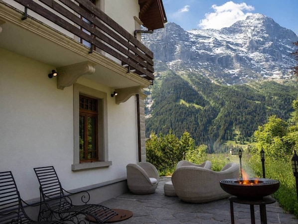 Une terrasse avec des siÚges extérieurs, un foyer et une vue sur les montagnes.