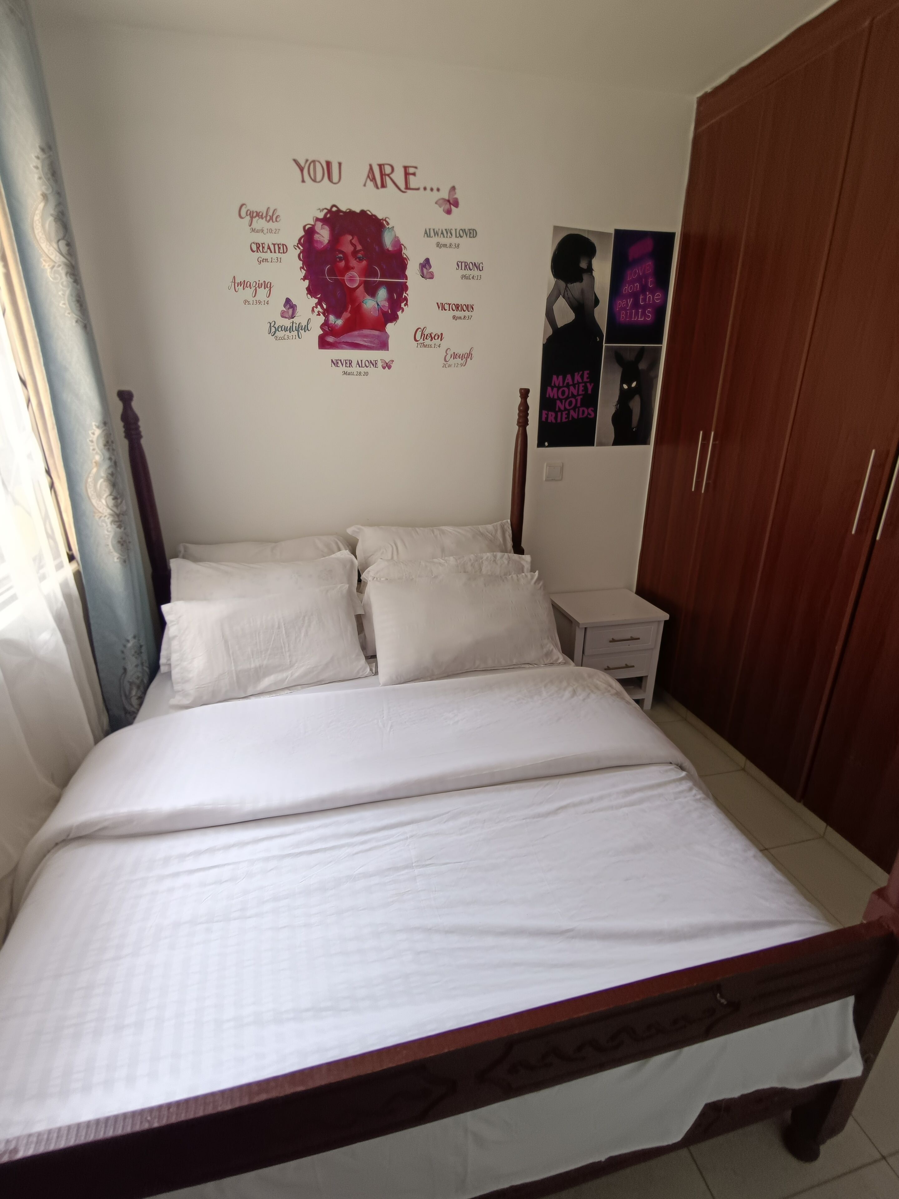 Ein Schlafzimmer mit einem Bett, einem Nachttisch, einem Kleiderschrank und motivierenden Postern an der Wand.