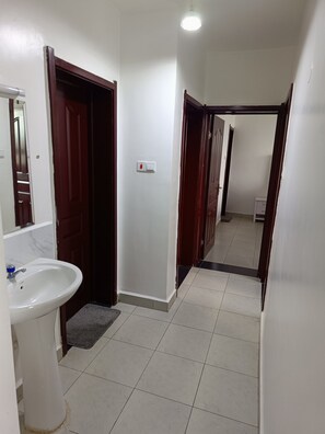 A hallway with a white sink, a mirror, and a door leading to another room. - Fantastic 2-bedroom apartment in tranquil Pridelands with AC (Pridelands)